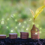 Coins stacked with a plant growing, symbolizing financial growth and investment.